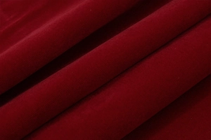 Primer plano de la textura de tela de terciopelo rojo oscuro con pliegues en un vestido evasé