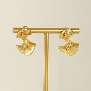 Irregular gold twisted earrings with crinkled texture on a minimalist metal display stand