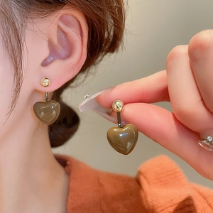 Close-up of brown heart-shaped stud earring with a glossy finish and golden metal pins