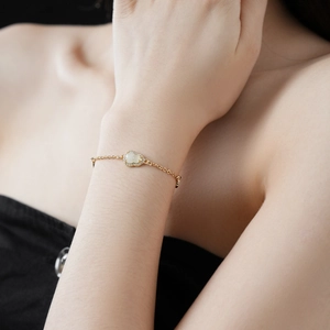 Detailed view of a gold gourd-shaped jade bracelet with zircon inlay on a woman wrist