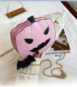 Detailed view of pink pumpkin bag with black facial patch and gold chain strap