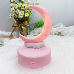 Macro detail of a pink crescent moon night light with a heart button on a white base
