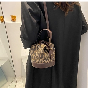 Rear view of a model wearing the brown leopard print bucket bag with leather trim