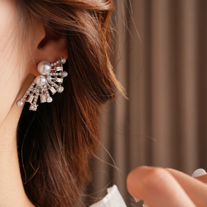 Detailed view of silver fan-shaped earrings with pearls and rhinestones on a model