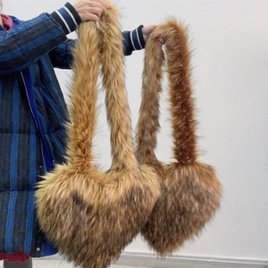 Detail of a brown faux fur heart-shaped crossbody bag featuring soft long-pile texture