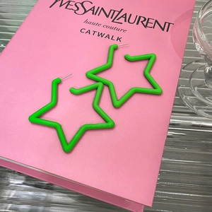Close-up of matte green star-shaped earrings on a pink book with elegant shadows