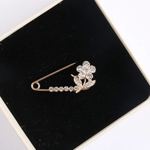 Close-up of golden floral brooch with clear crystals on a black velvet display