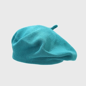 Detailed texture of a teal knitted cotton beret with a classic top stem design