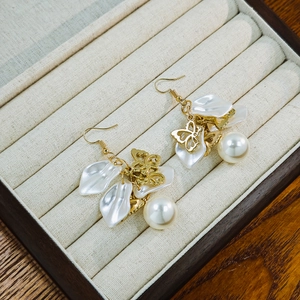 Detail view of French vintage floral earrings with pearls and gold butterfly charms