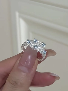 Detail of silver irregular ring with blue zircon clusters on finger with textured edges