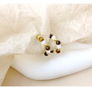 Detailed view of handmade beaded ring with tiger eye stones and golden metal spacers