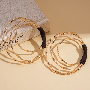Golden multi-layer geometric hoop earrings with black thread wrap on a beige background
