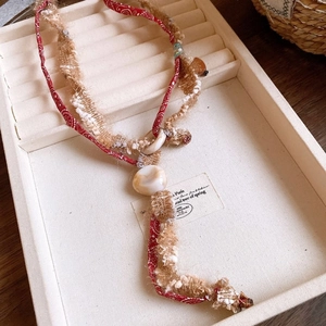 Dettaglio macro di collana bohémien con tessuto paisley rosso e cordoncini intrecciati