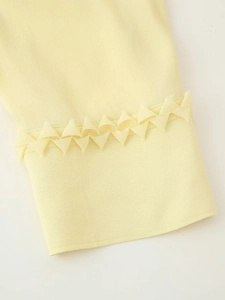 Detail view of light yellow blouse sleeve with unique 3D triangle folded edge decoration