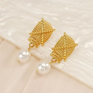 Detail showing cross-embossed gold finish and glossy white pearl on the drop earring