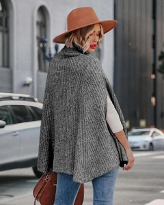 Dettagli della trama a maglia del poncho grigio-nero a collo alto su una modella di moda