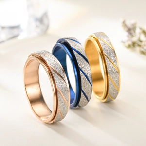 Three frosted spinner rings in rose gold, blue, and gold with diagonal textured lines