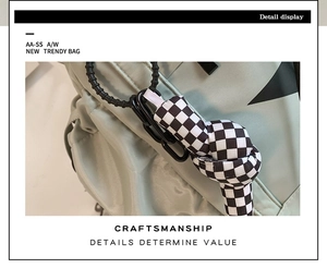 Detail view of the green shoulder bag featuring checkerboard knot and black chain link