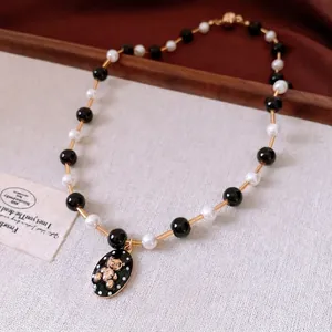 Elegant beaded pearl necklace with black bear pendant and gold accents on velvet