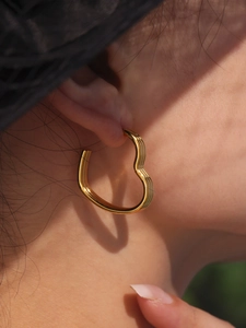 Close-up of golden heart-shaped stainless steel hoop earrings with polished finish