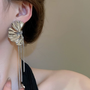Macro detail of silver ginkgo leaf earrings with long metal fringe tassels on model