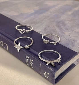 Detail of four silver S925 rings with heart and star designs on a dark blue book