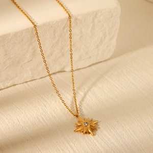 Detail view of a gold starburst pendant with a clear gem on a classic O-link chain