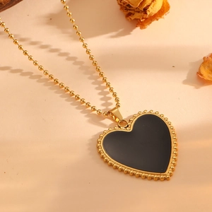 Detailed view of heart pendant necklace with gold beaded chain and black shell inlay