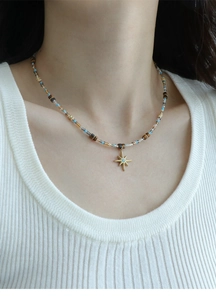 Detail of beaded necklace with tiger eye stones and a gold star pendant on a model
