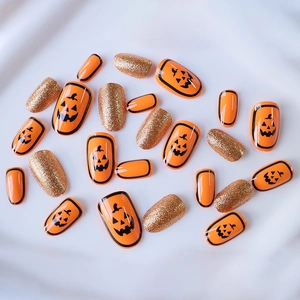 Short oval Halloween press-on nails featuring orange pumpkin faces and gold glitter designs