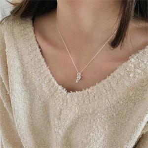 Detail view of a 925 sterling silver knot pendant necklace worn on a female model