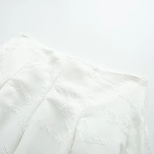 Gros plan détaillé sur les franges blanches et la texture plumes de cet ensemble jupe