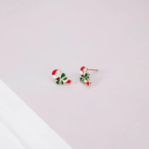 Macro detail of Christmas candy cane stud earrings with green bow and gold plating
