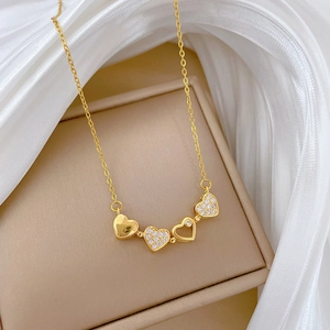 Detail of gold clover necklace with diamonds on silk fabric within a beige jewelry box