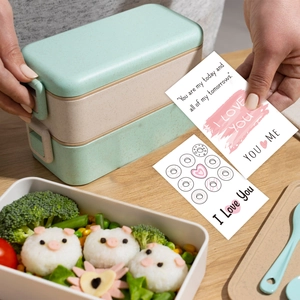 Boîte à lunch verte avec cartes de vœux inspirantes sur une table en bois