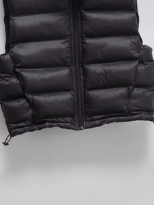 Close-up detail of black padded vest featuring horizontal quilting and adjustable drawstring