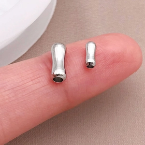 Macro di piccoli connettori a perla di bambù argento sulla punta del dito per gioielli fai-da-te