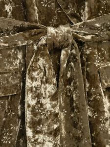 Detail of velvet suit jacket showing olive green floral print with belt and pocket