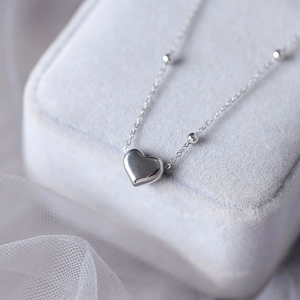 Macro shot of silver heart pendant necklace on light gray velvet jewelry display box