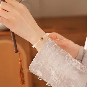 Elegant white crystal beaded bracelet with a gold hollow floral charm on a woman's wrist