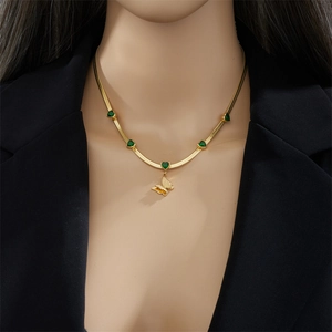 Collana a catena dorata con gemme a cuore verdi e ciondolo a farfalla su modella