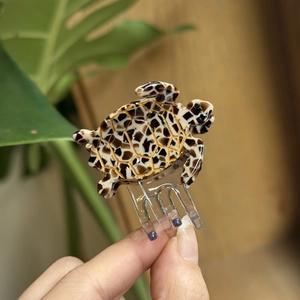 Detailed close-up of a small tortoise-shaped hair claw clip with brown marble pattern
