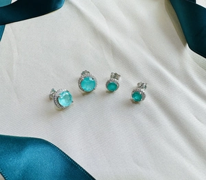 Close-up of silver Halo stud earrings with round emerald-cut stones on silk and ribbon