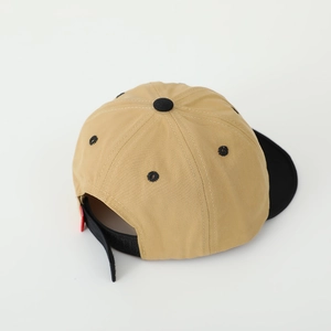 Détail d'une casquette bicolore montrant la sangle réglable noire et le bouton supérieur