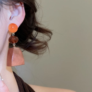Close-up of vintage geometric drop earrings with amber and resin elements on model