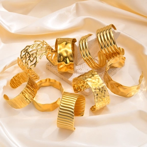 Detail of diverse gold plated stainless steel open bangles on silk and stone