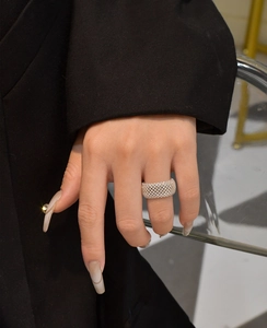 Macro shot of wide pavé mesh ring in gold finish on finger with a black blazer