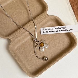 Detail of silver snake chain necklace with five-petal flower tiger eye stone pendant