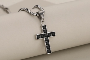Detailed macro view of silver stainless steel cross pendant with black gemstone inlay