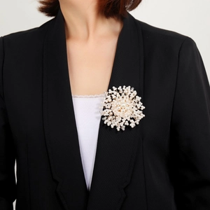 Detailed view of a handmade snowflake brooch with pearls and crystals on a black blazer lapel